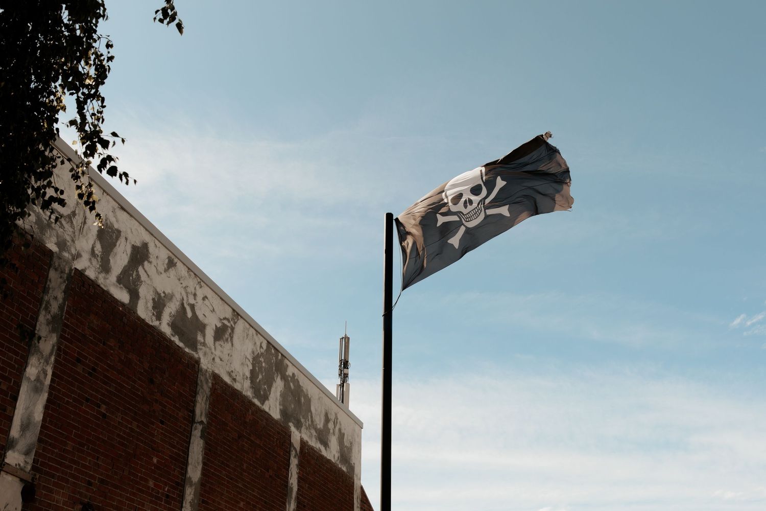 A flag waving against blue sky with brick building edge visible.