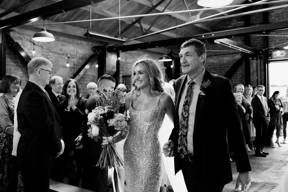 Black and white photo of wedding celebration in an industrial indoor venue.
