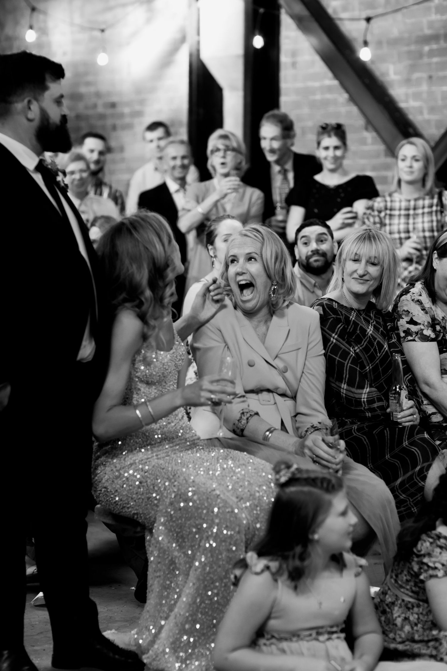 Black and white photo capturing joyful reactions during wedding speeches.