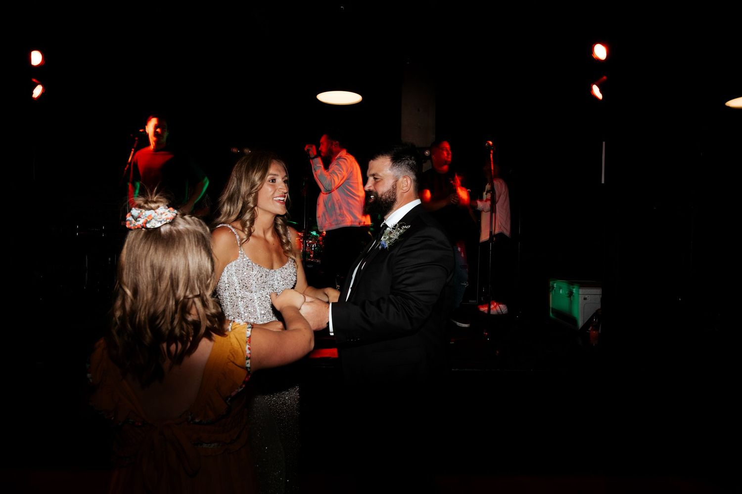 A romantic first dance moment at a wedding reception in a dark, intimate setting.