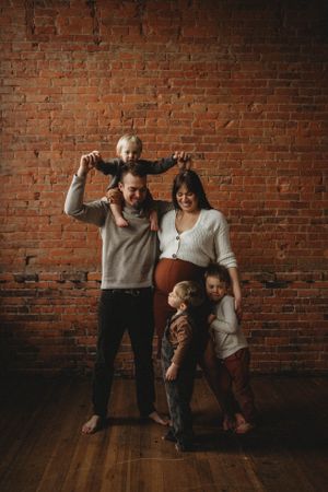 Family portrait against a brick wall showing playful poses and casual outfits.