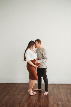 Intimate moment between couple in casual wear on wooden floor.