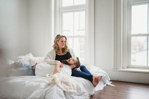 Candid shot of a couple sharing a joyful moment while laying on crisp white bedding.