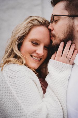 Intimate close-up portrait of a couple embracing in warm white knit sweaters.