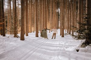 Distant couple walking through a snowy pine forest on a winter day.