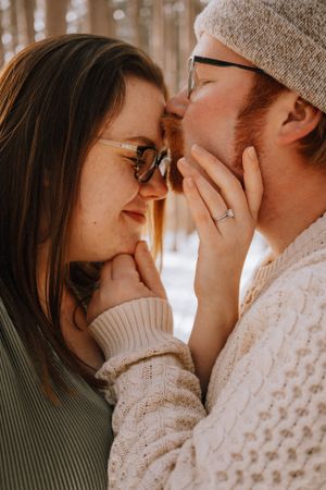A tender romantic moment between a couple in winter wear sharing a close embrace.
