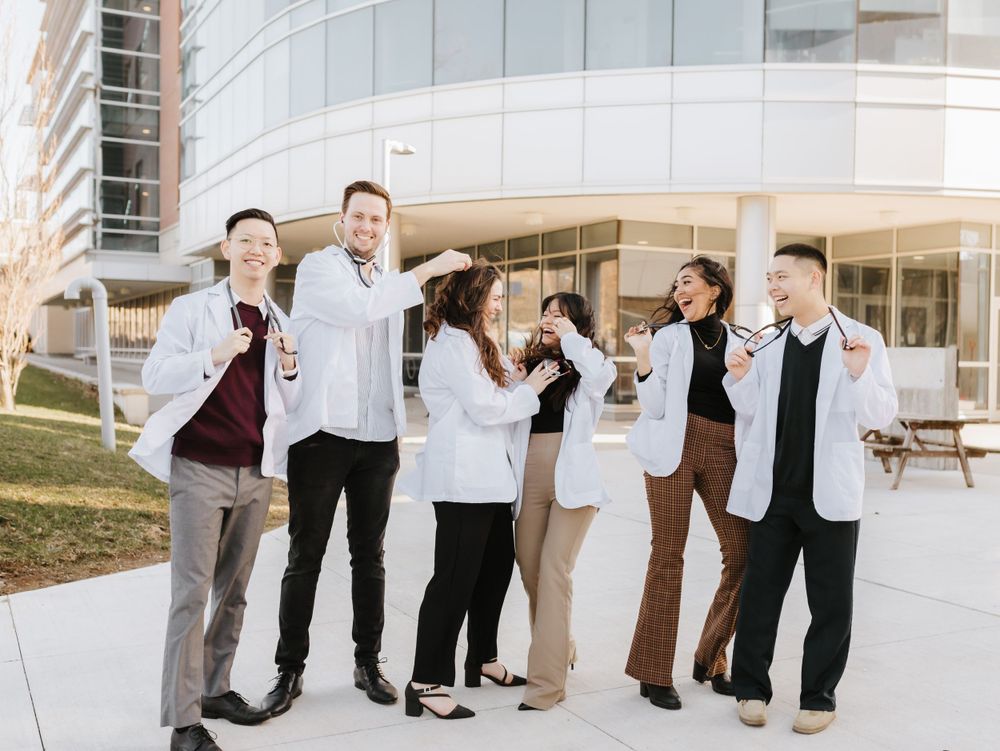 Group photo session outside modern glass building with coordinated formal attire.