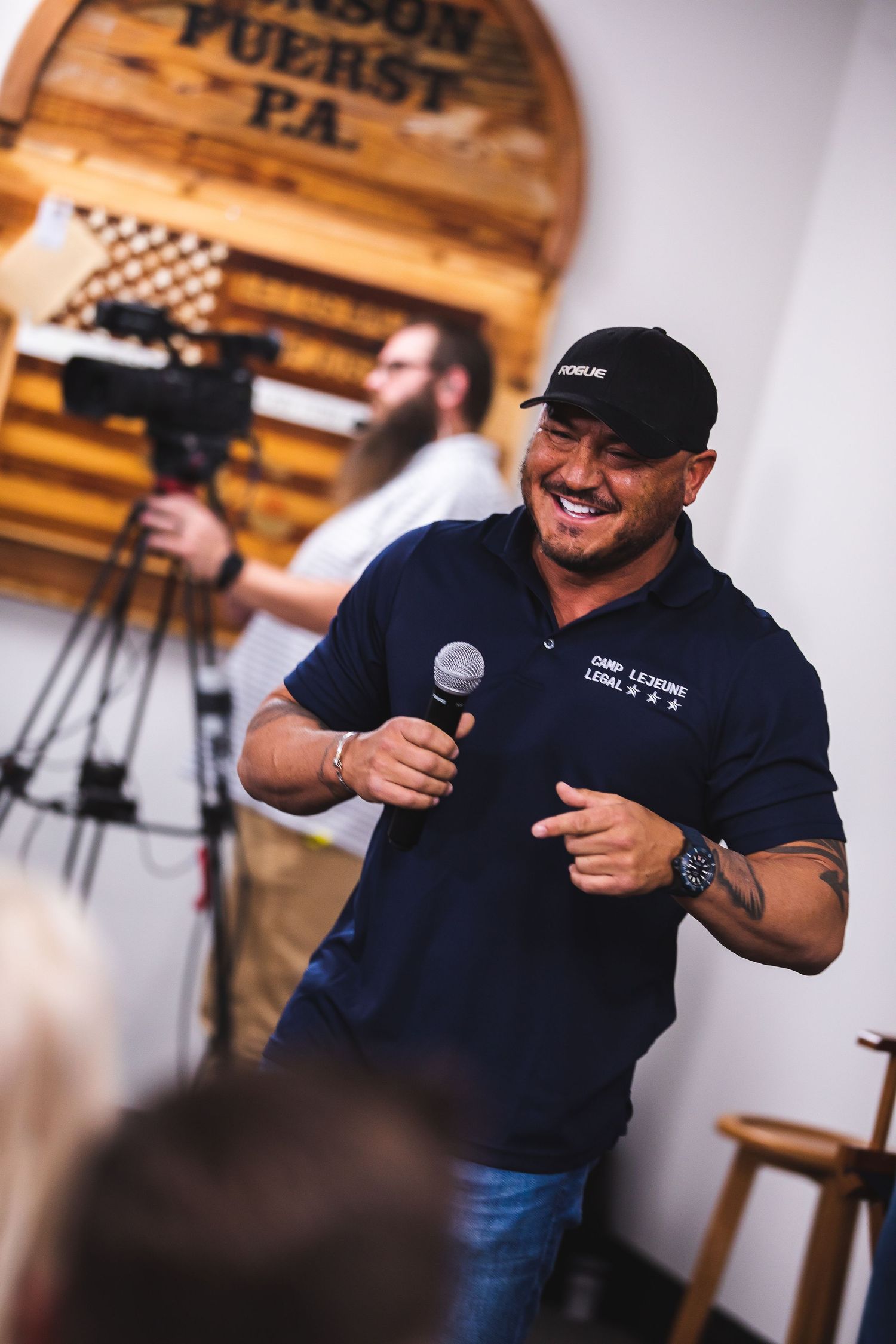 Event speaker presenting on stage with wooden barrel decor in background.