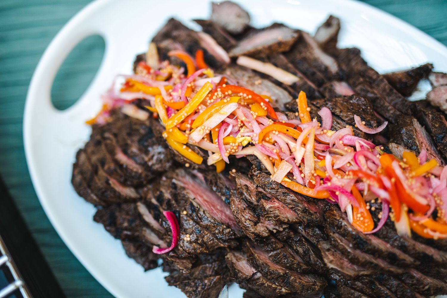 Sliced beef with colorful pickled vegetables on white serving plate.