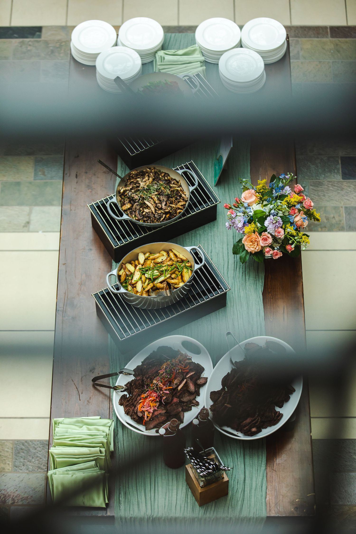 Overhead view of Asian dishes served on dark plates with white dinnerware and floral accent.