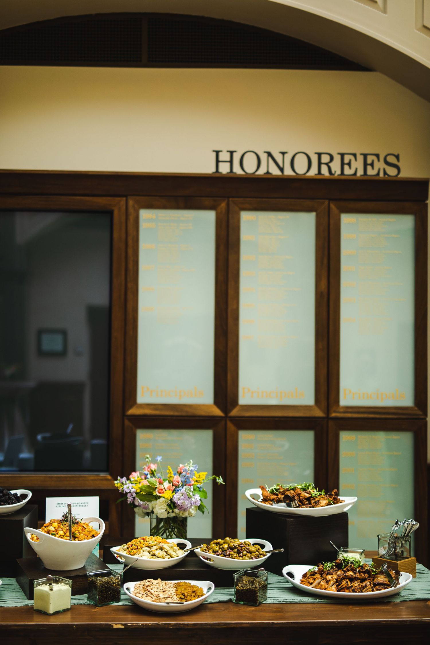 Elegant buffet display under a Honorees sign featuring multiple dishes and floral arrangements.