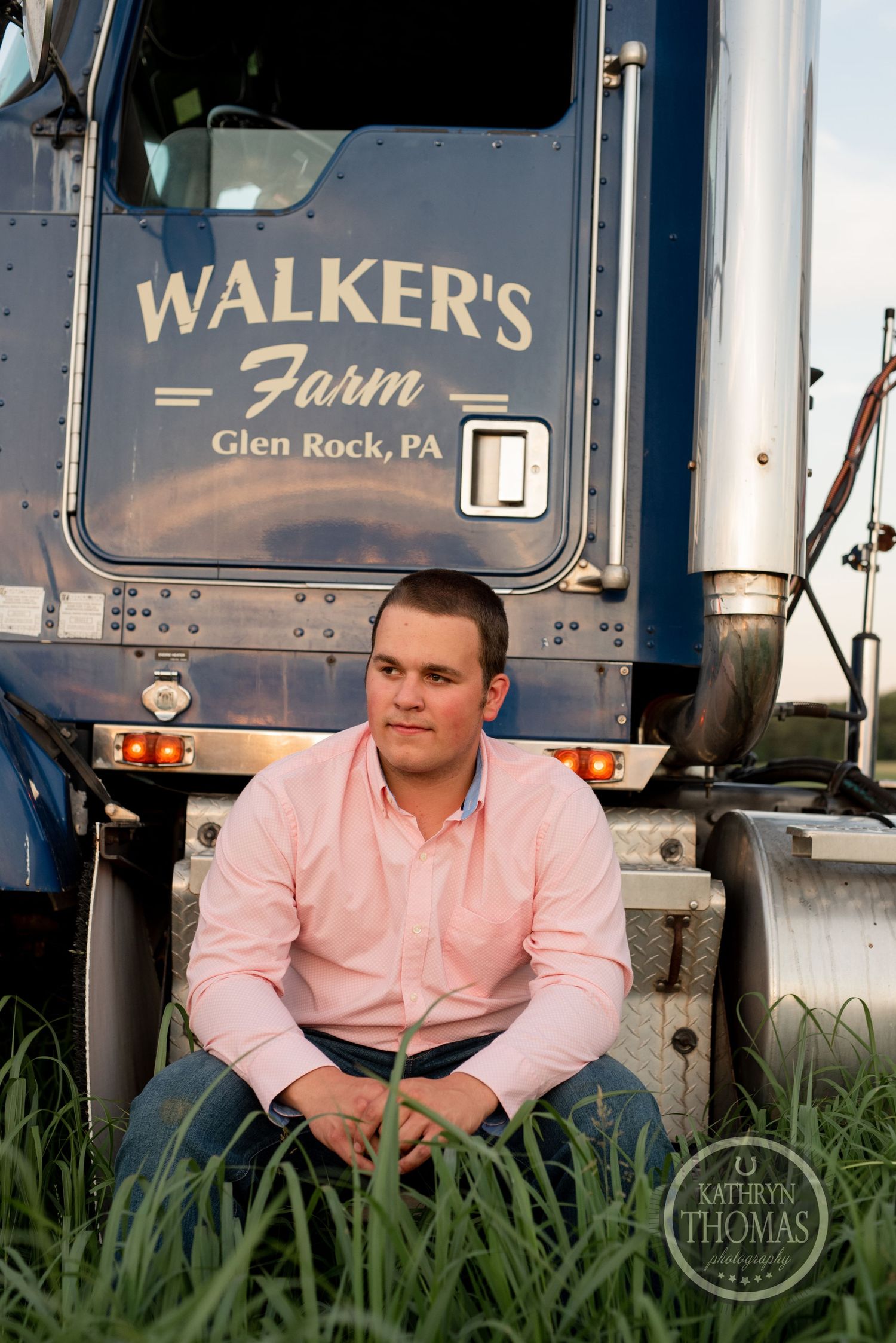 Portrait of driver sitting by Walker's Farm truck from Glen Rock, PA in tall grass.