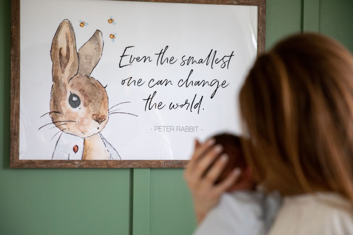 Watercolor bunny artwork with inspirational quote hangs on green wall.
