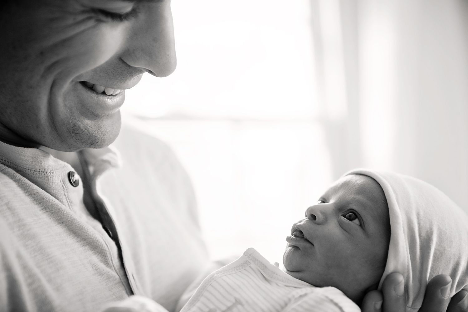 Black and white photo showing tender moment between parent and newborn.