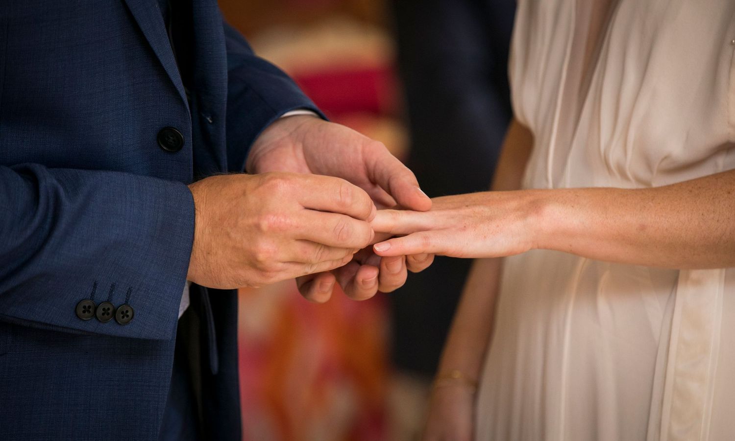 Close-up of hands during wedding ring exchange ceremony.