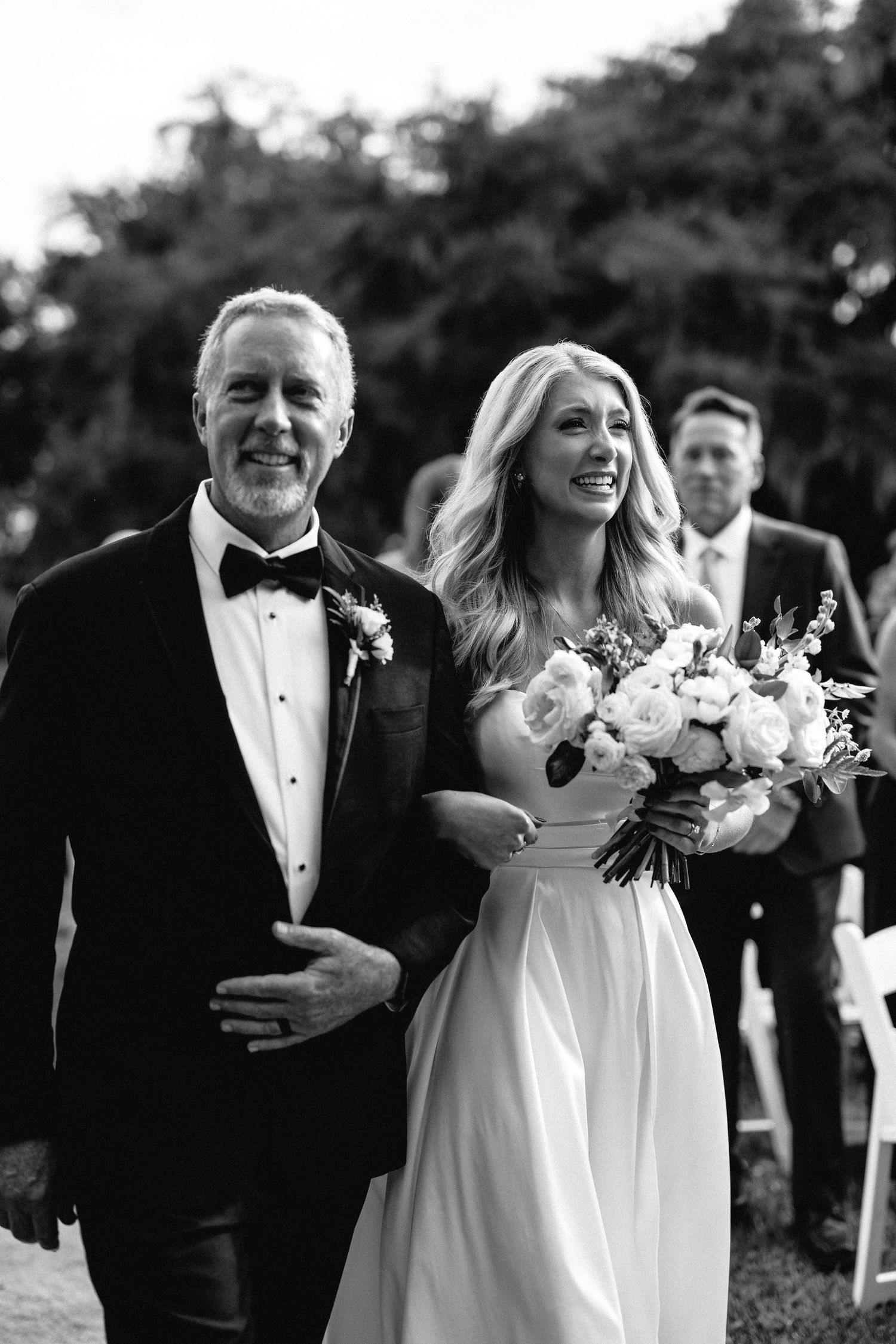An emotional bride, walking down the aisle with her proud father during a ceremony at Middleton Place Gardens, Charleston, SC