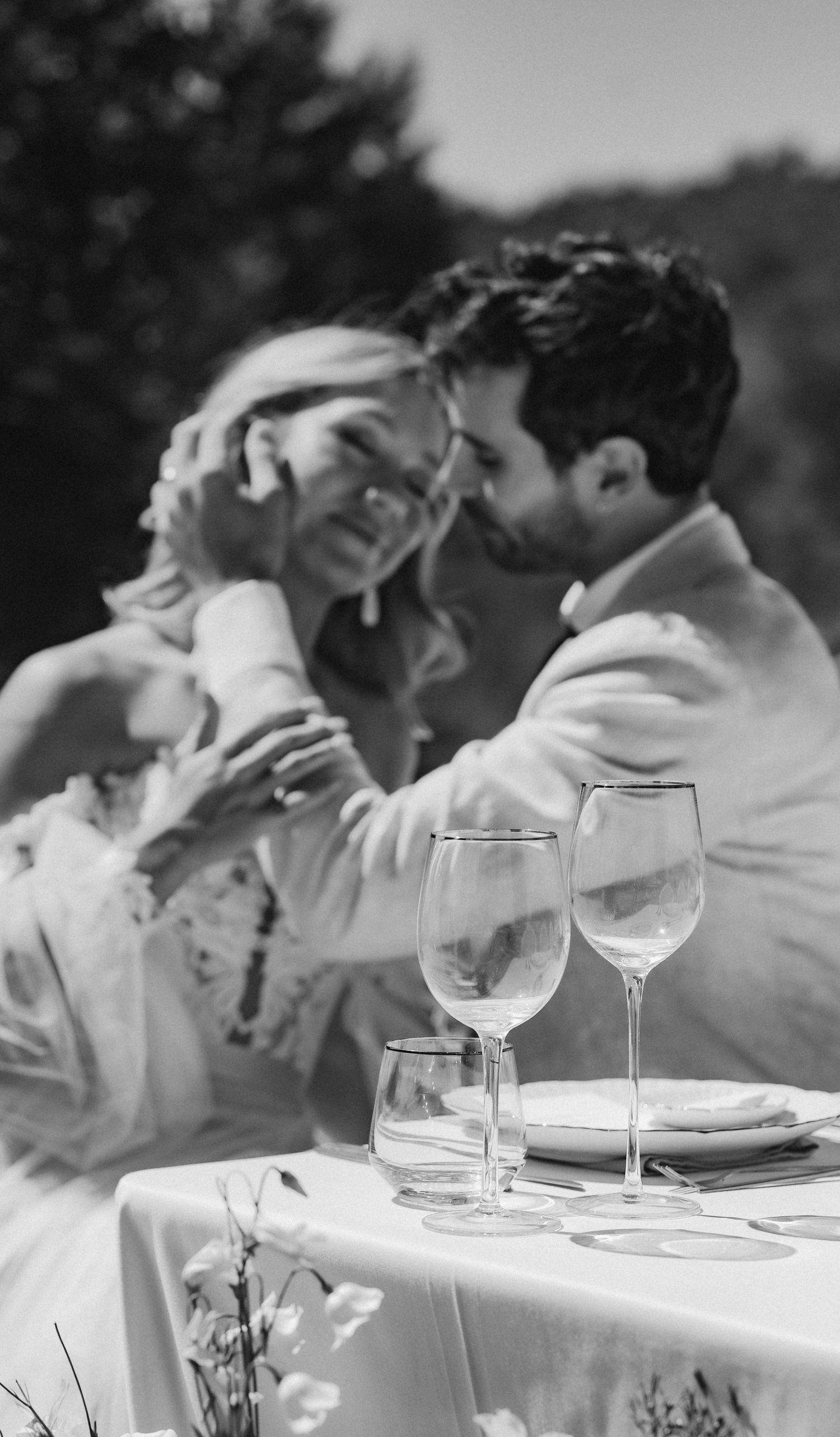 Elegant outdoor wedding table setting with wine glasses and white linens in black and white.