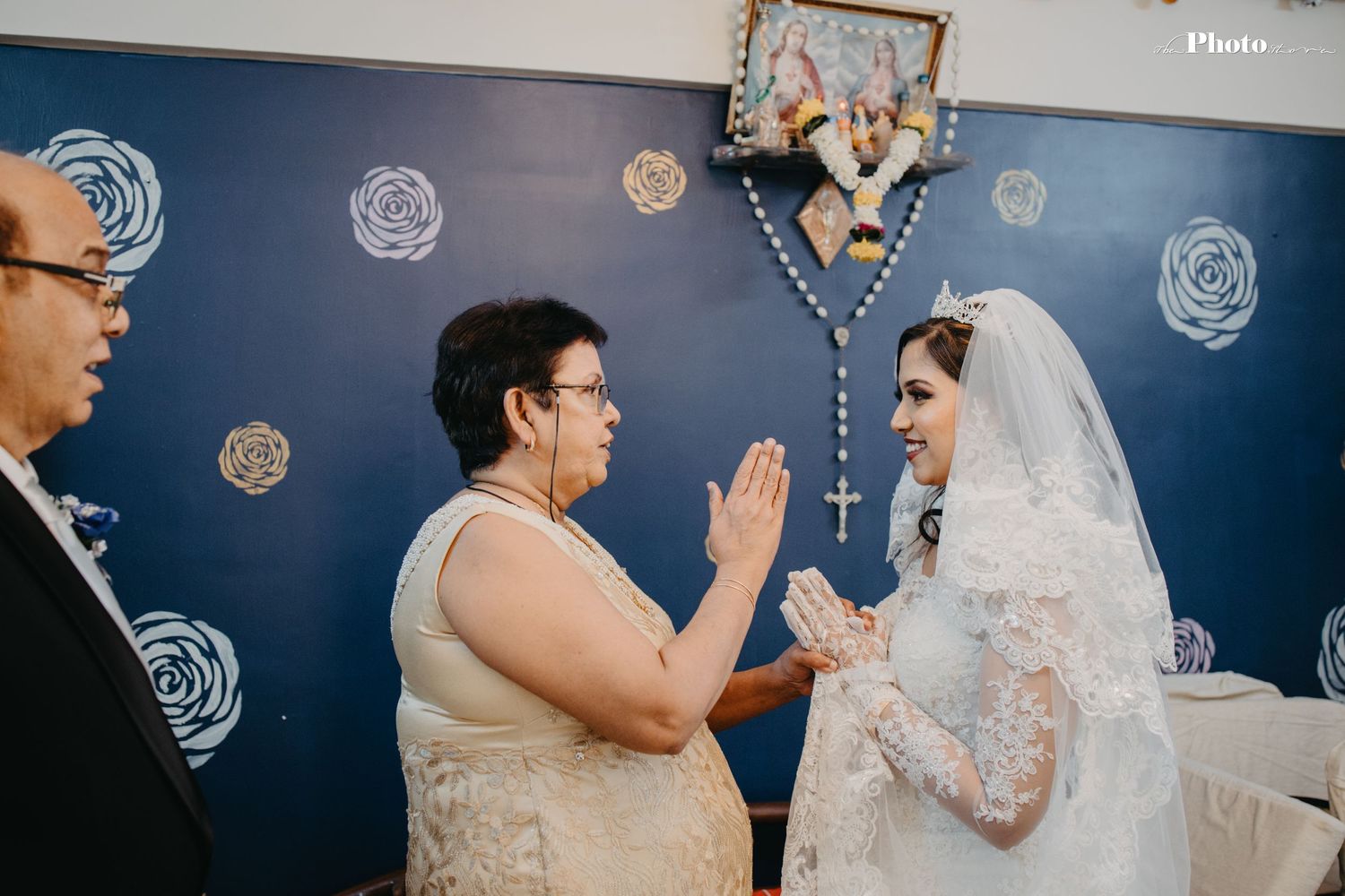 Wedding ceremony scene with guests and decorative rose-patterned blue backdrop.