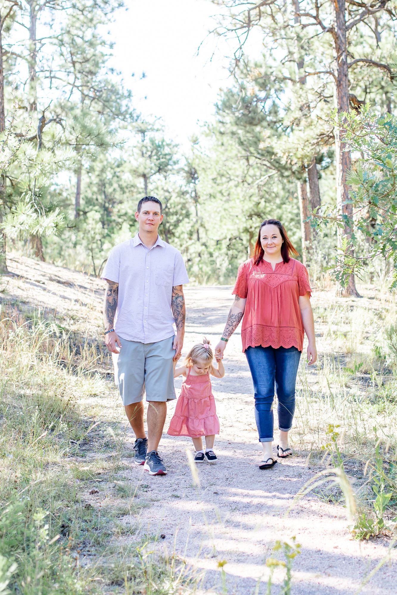 Dad and mom lead their toddler daughter down the trail in Black Forest, Colorado.