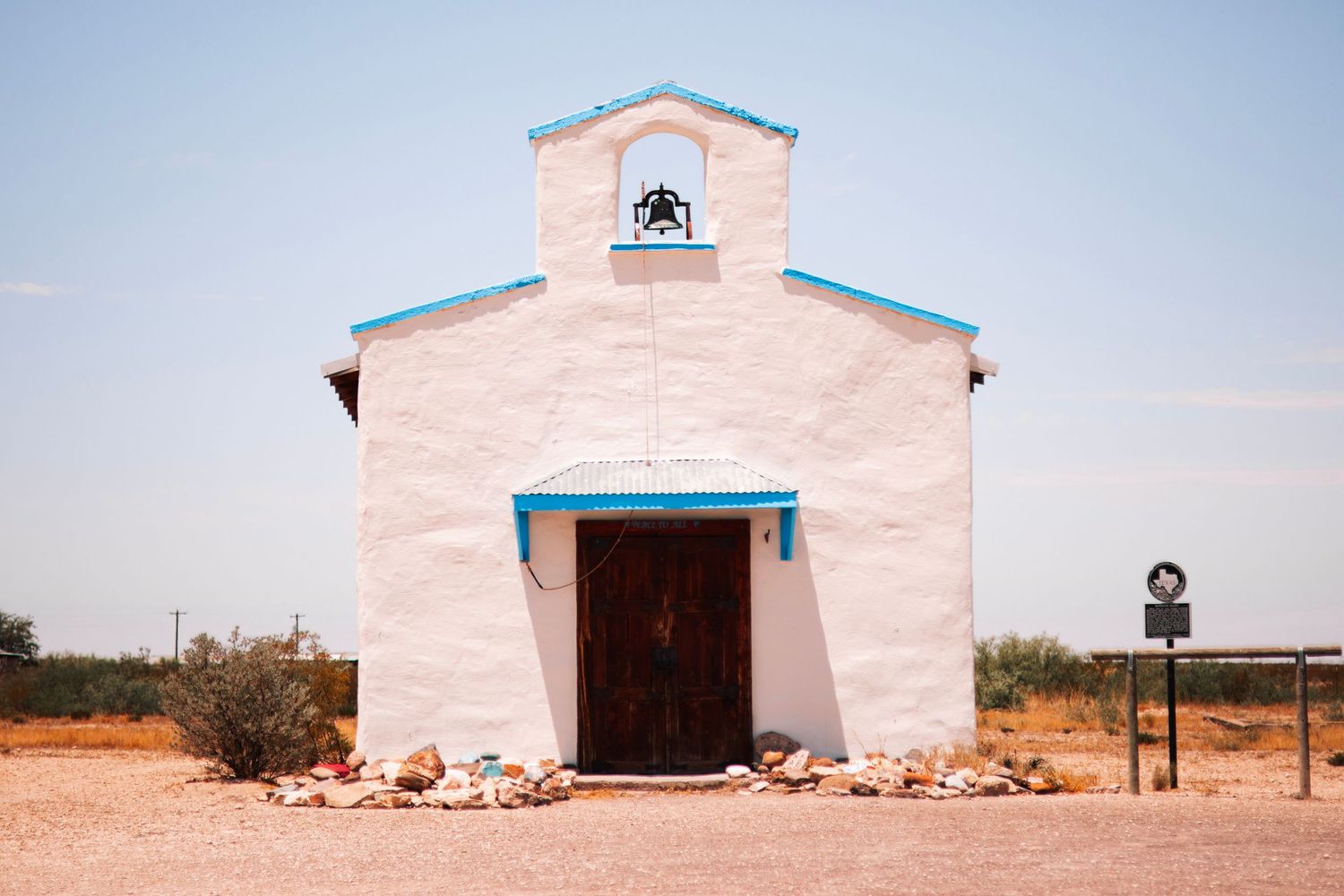 A pink and blue trimmed church building photographed from different angles on an open landscape.