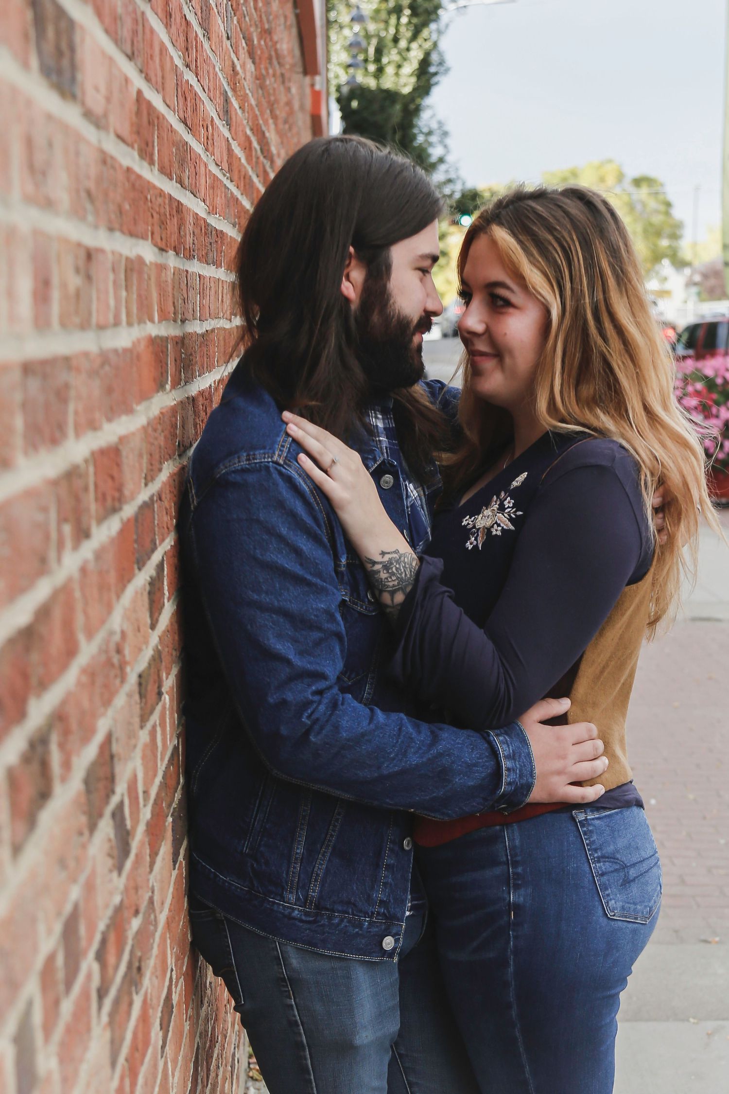 Engagement photo session with couple leaning against a brick wall