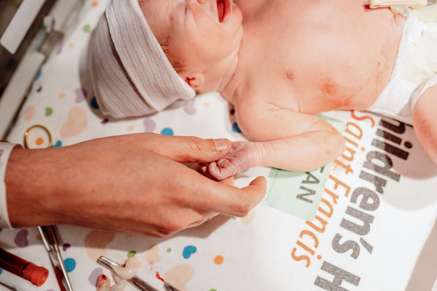 newborn baby girl holding her dads finger after birth in tulsa