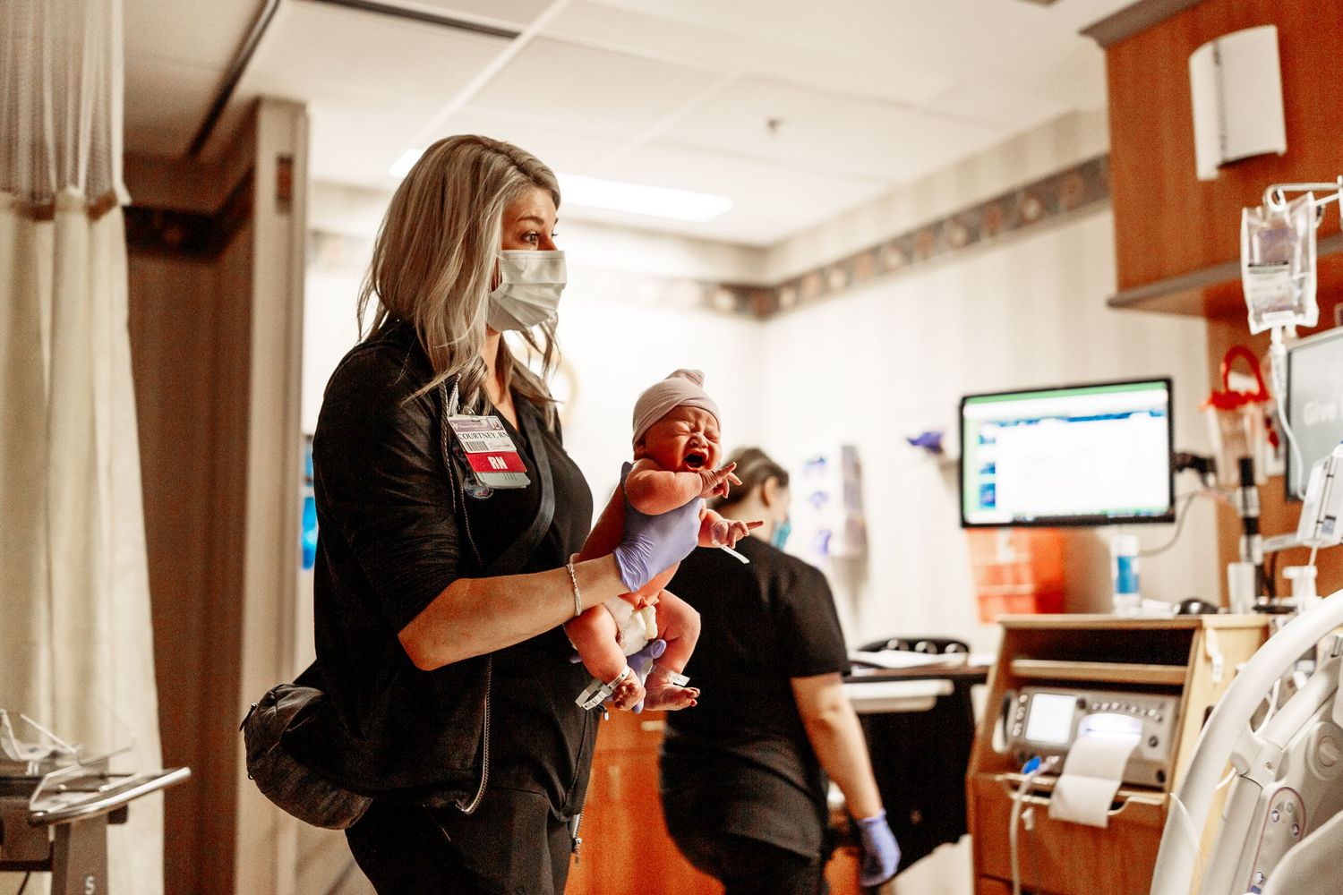 Tulsa birth photographer newborn nurse holding newborn baby at Hillcrest hospital in Tulsa, OK
