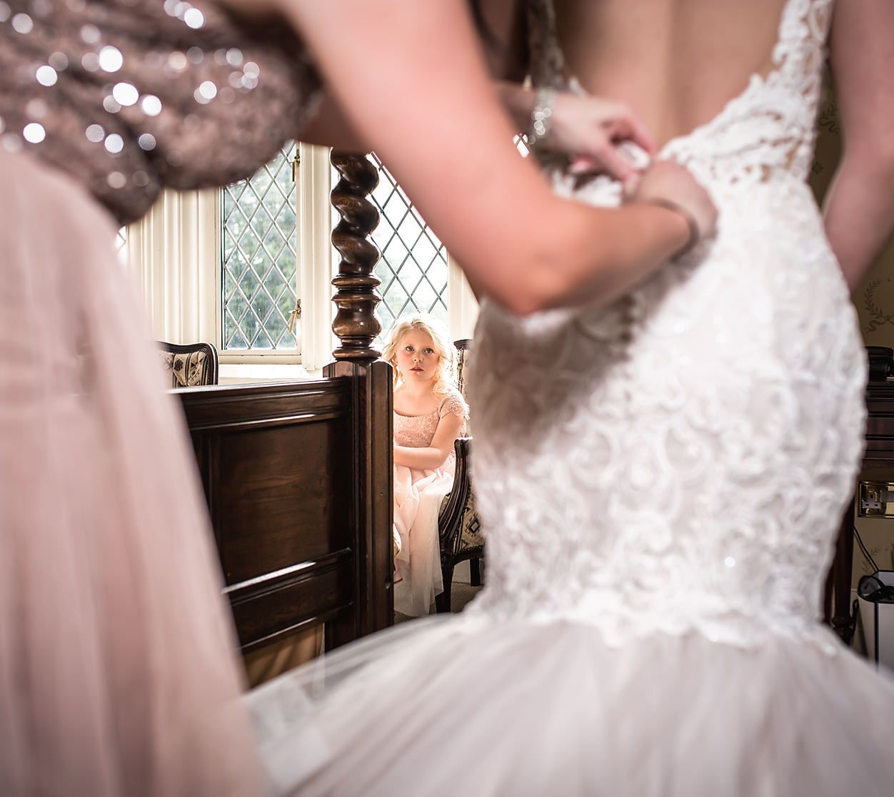 Close-up detail of intricate lace wedding dress with window reflection.