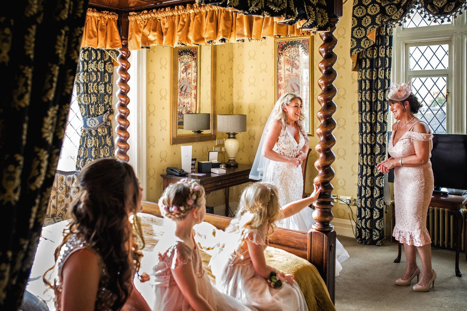 Bridal preparation scene in vintage room with bridesmaids in pink dresses.