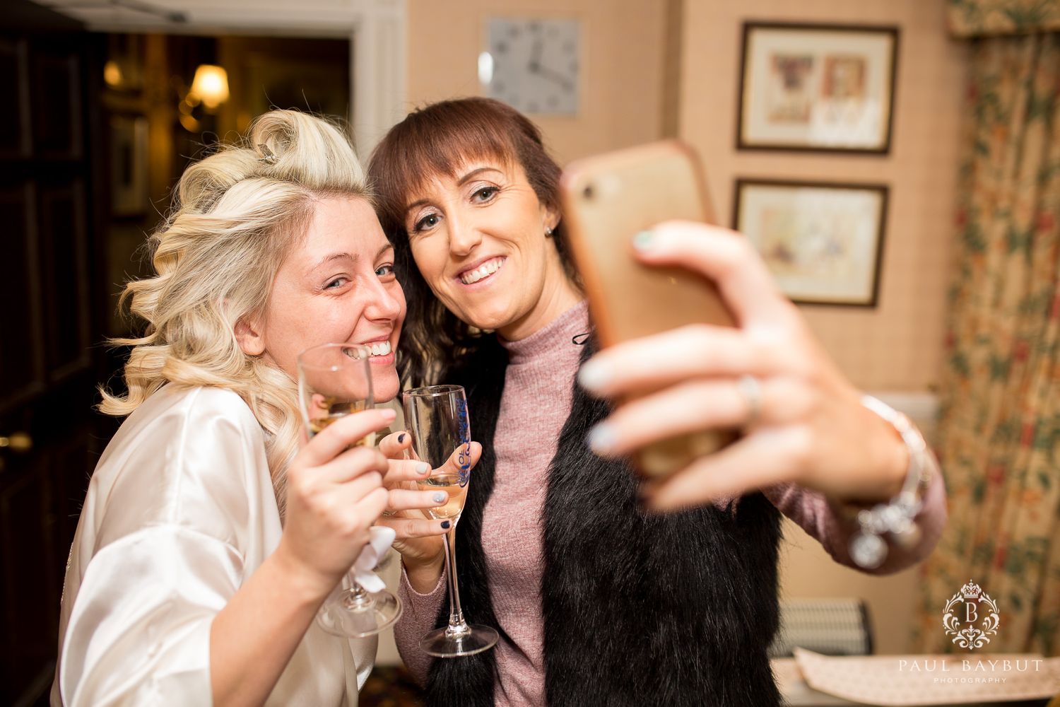 Two friends taking a selfie while enjoying champagne at a celebration.