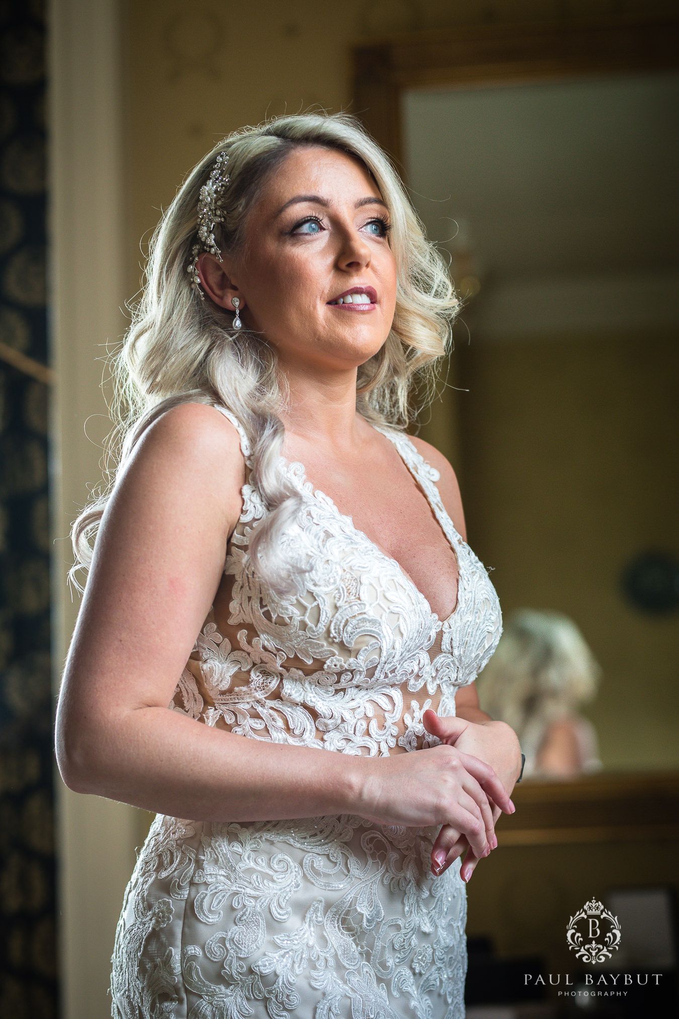 Elegant bridal portrait showcasing intricate lace wedding dress and soft window lighting.