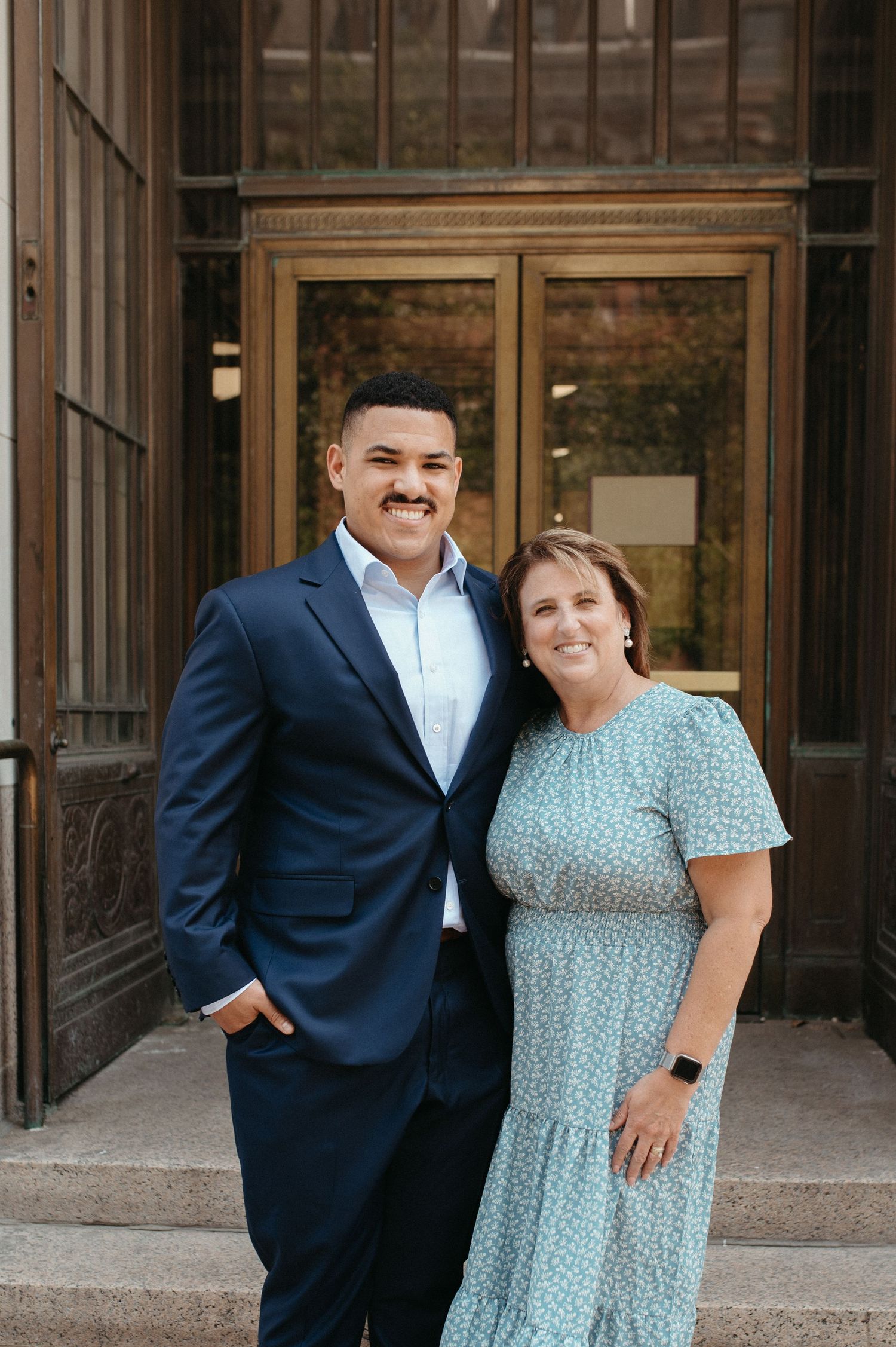 Formal portrait of a pair in navy suit and mint dress against wooden doors.
