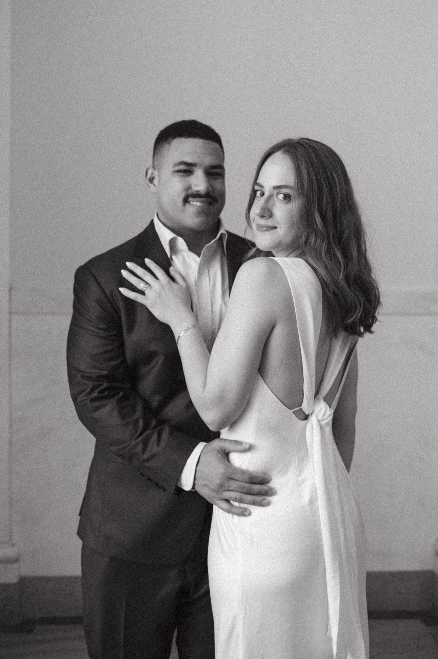 Black and white portrait of couple embracing in formal wedding attire.