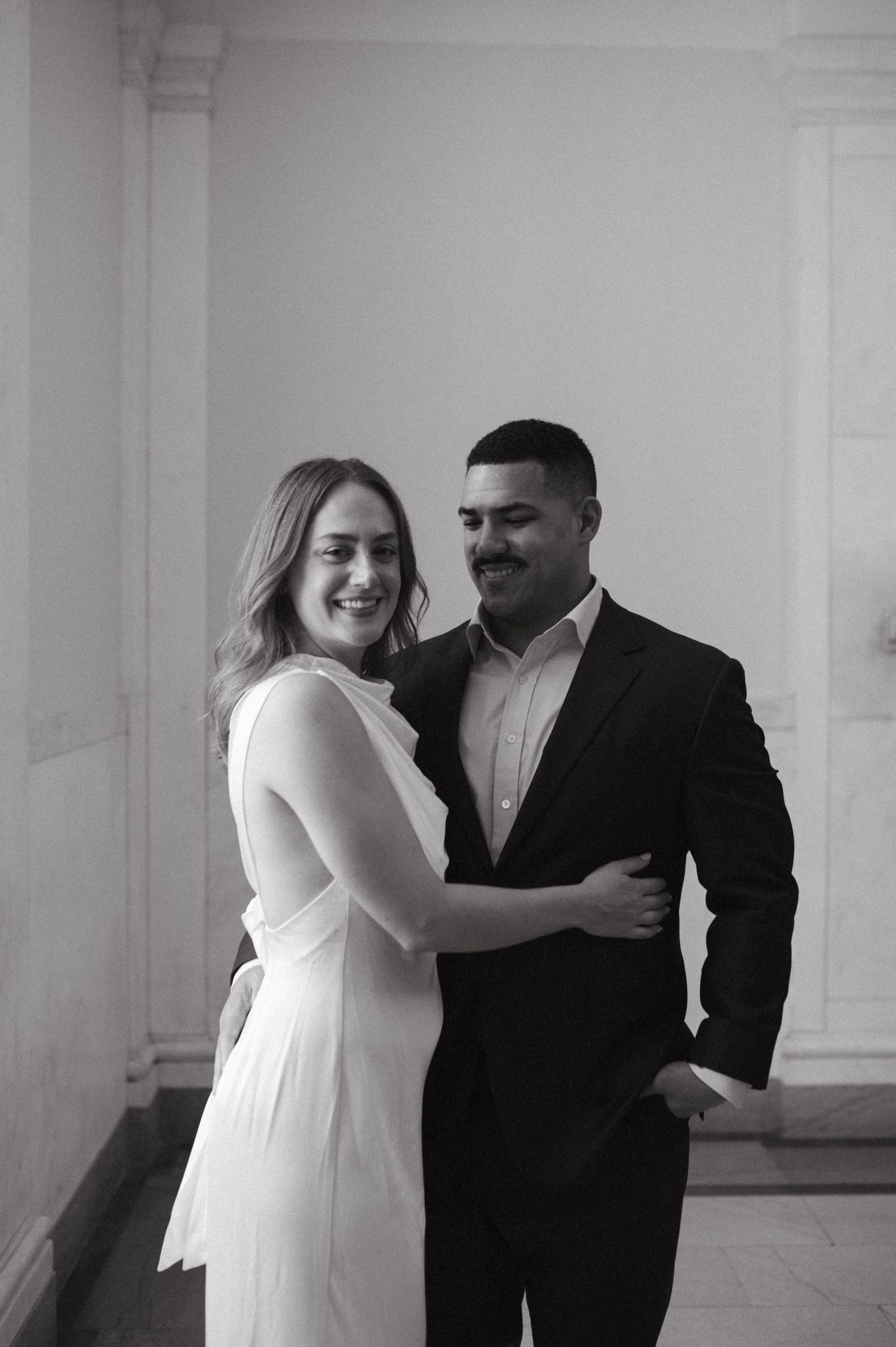A joyful black and white portrait of a couple laughing together in an elegant indoor setting.