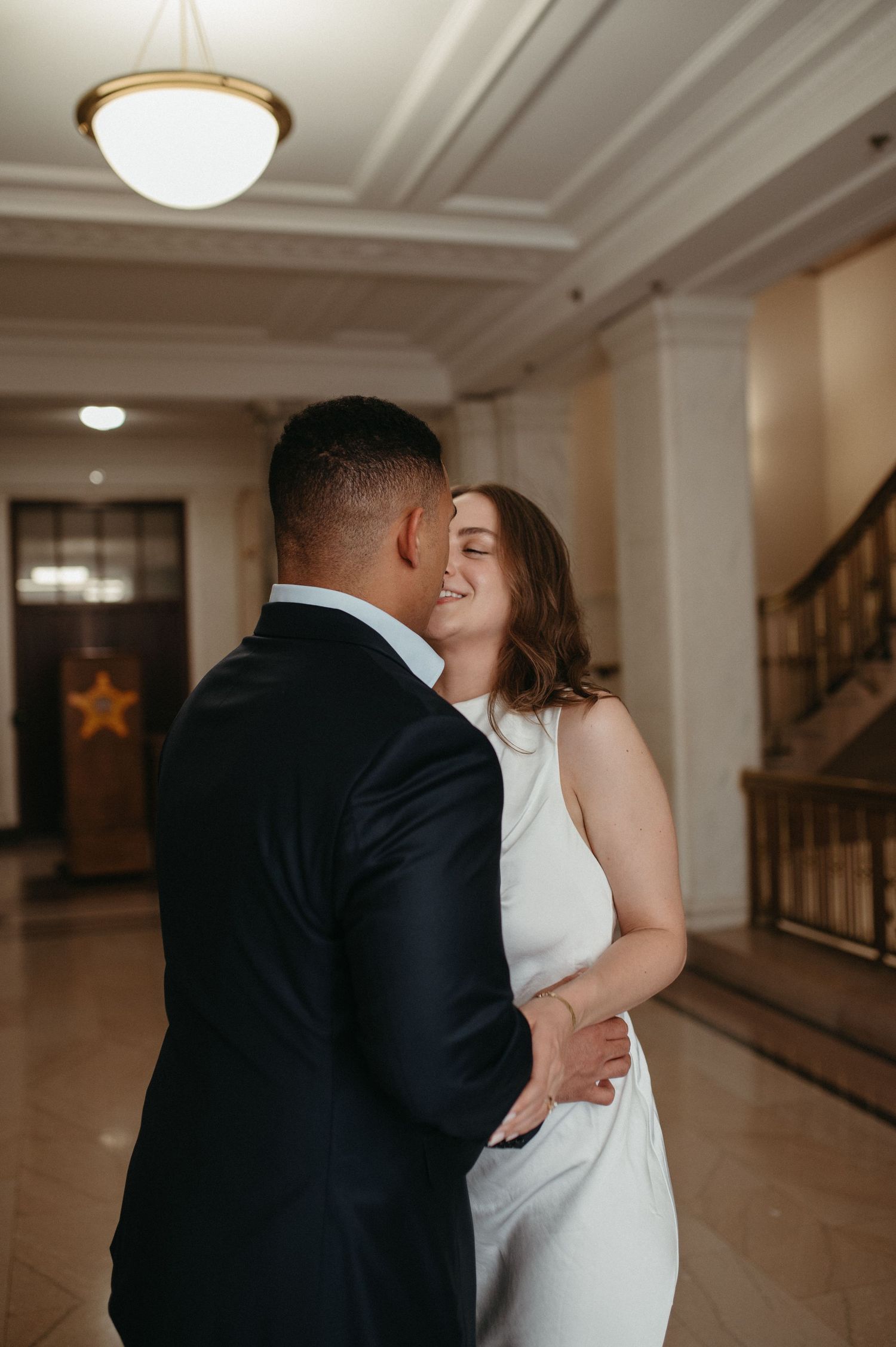 A tender moment between newlyweds sharing an embrace in a classic architectural setting.