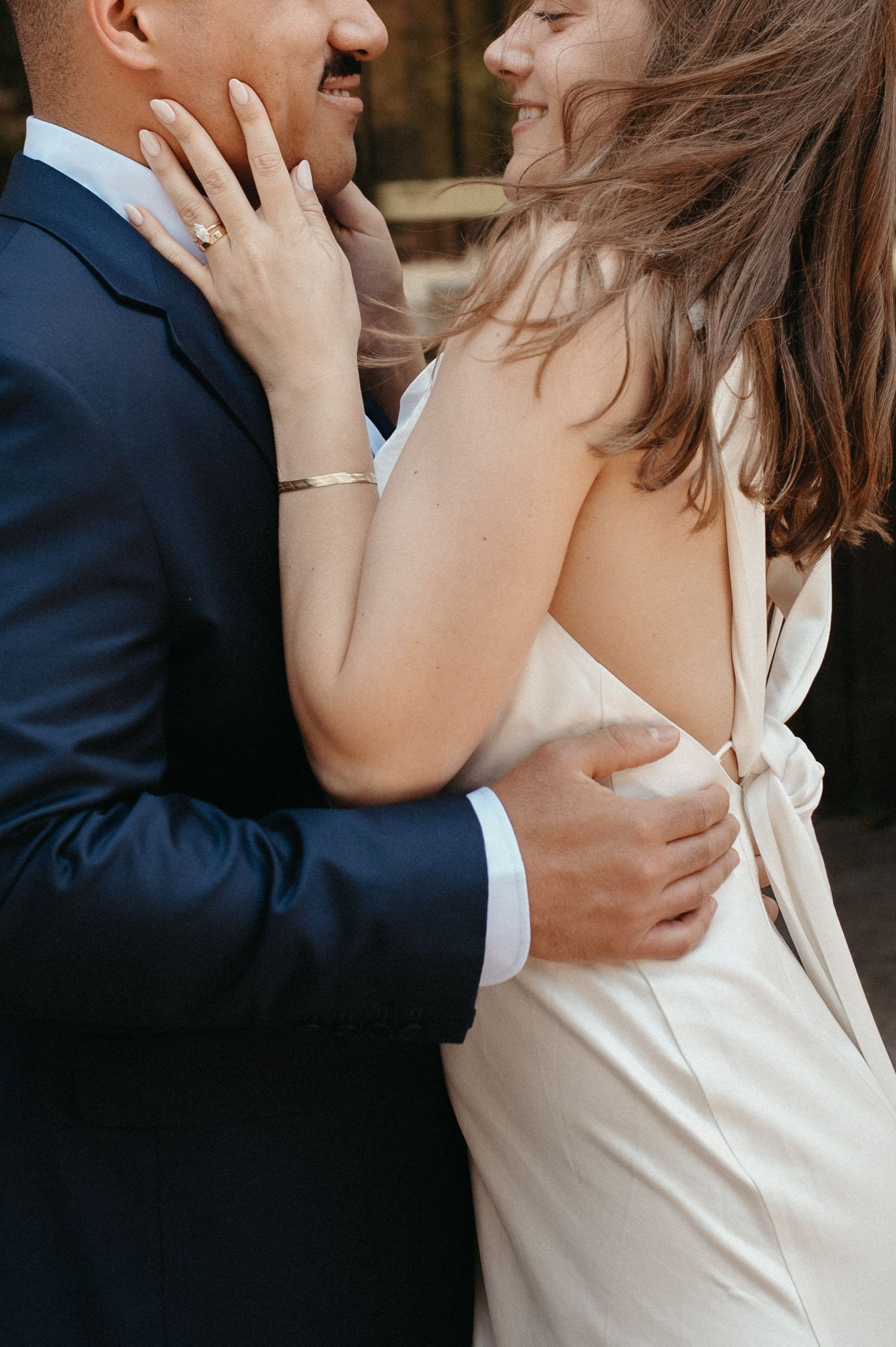 Close-up of couple embracing, showing engagement ring and formal attire.