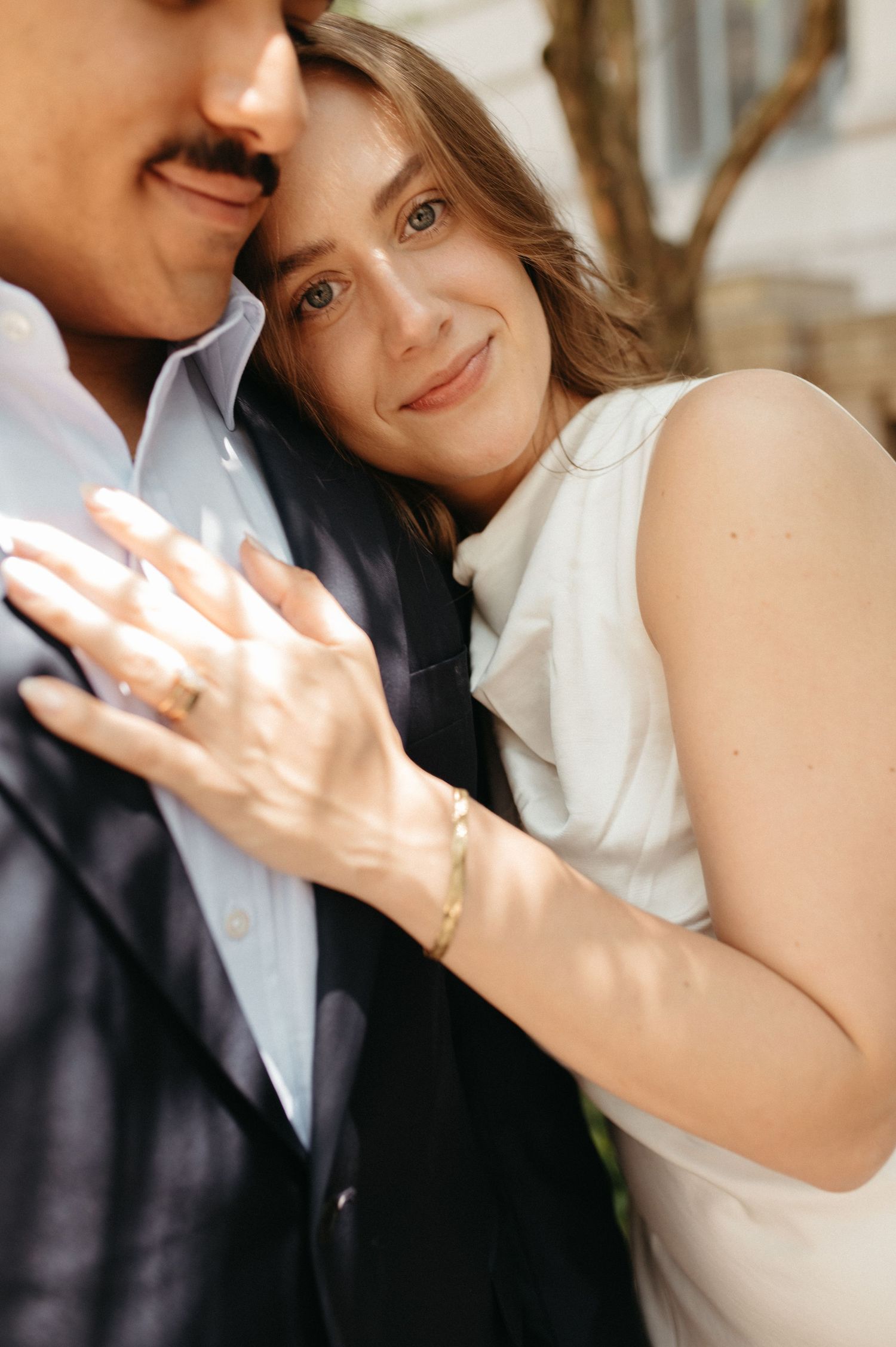 Close-up of couple showing engagement ring and sharing intimate moment.