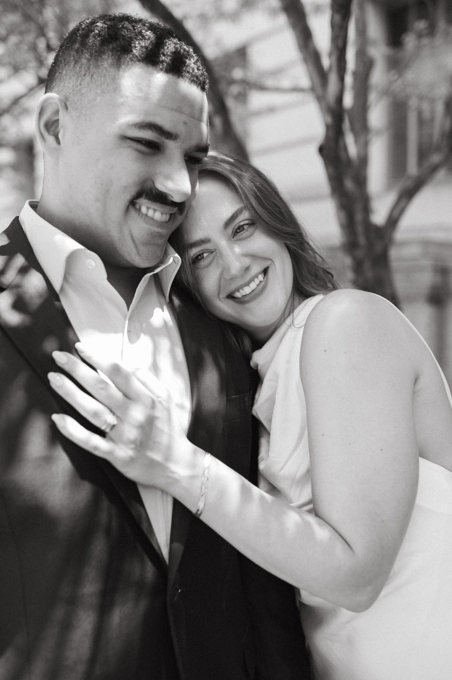A romantic black and white portrait of a couple sharing a joyful embrace outdoors.