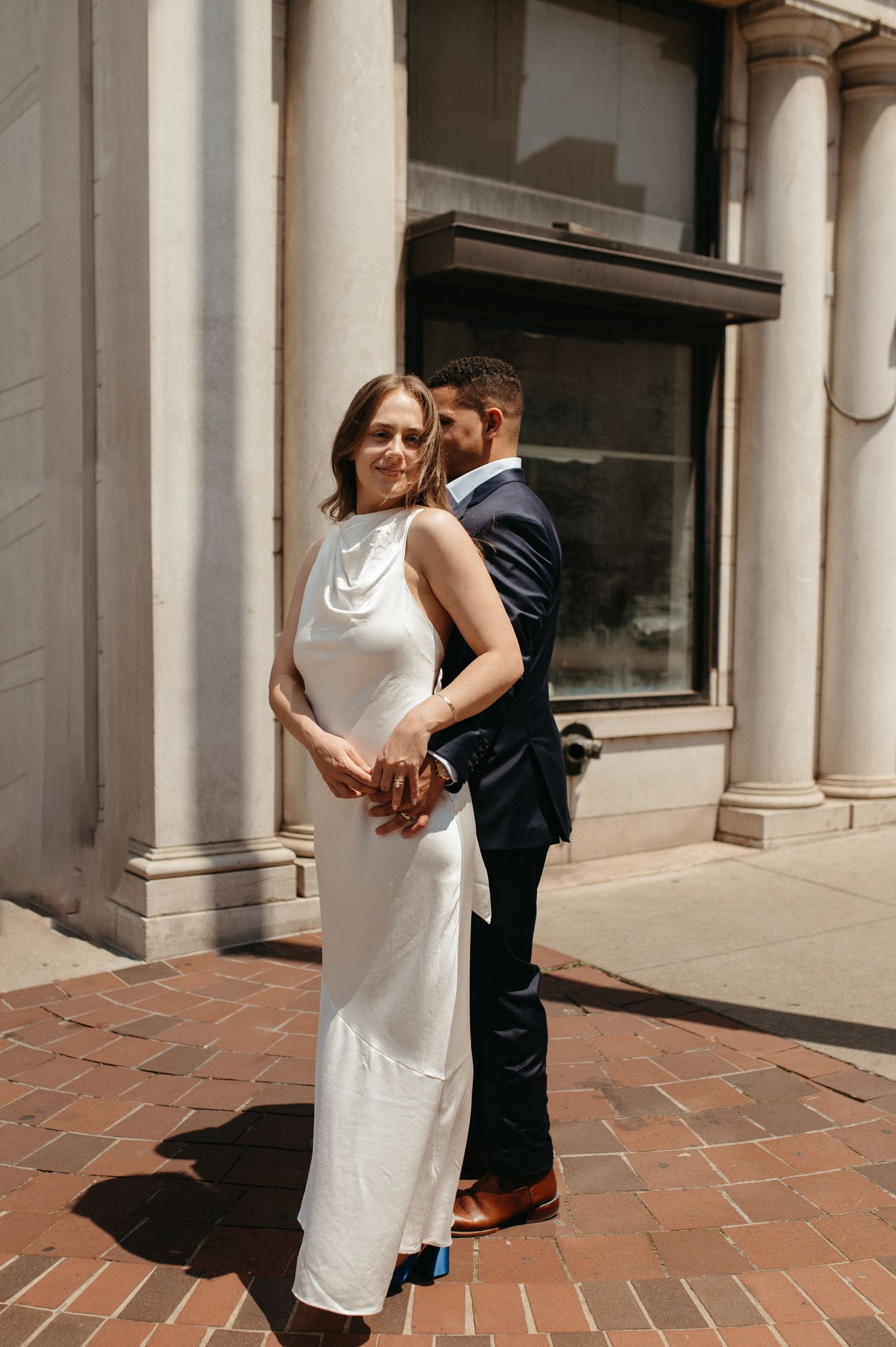 Intimate wedding portrait of couple in elegant attire against classic architectural backdrop.