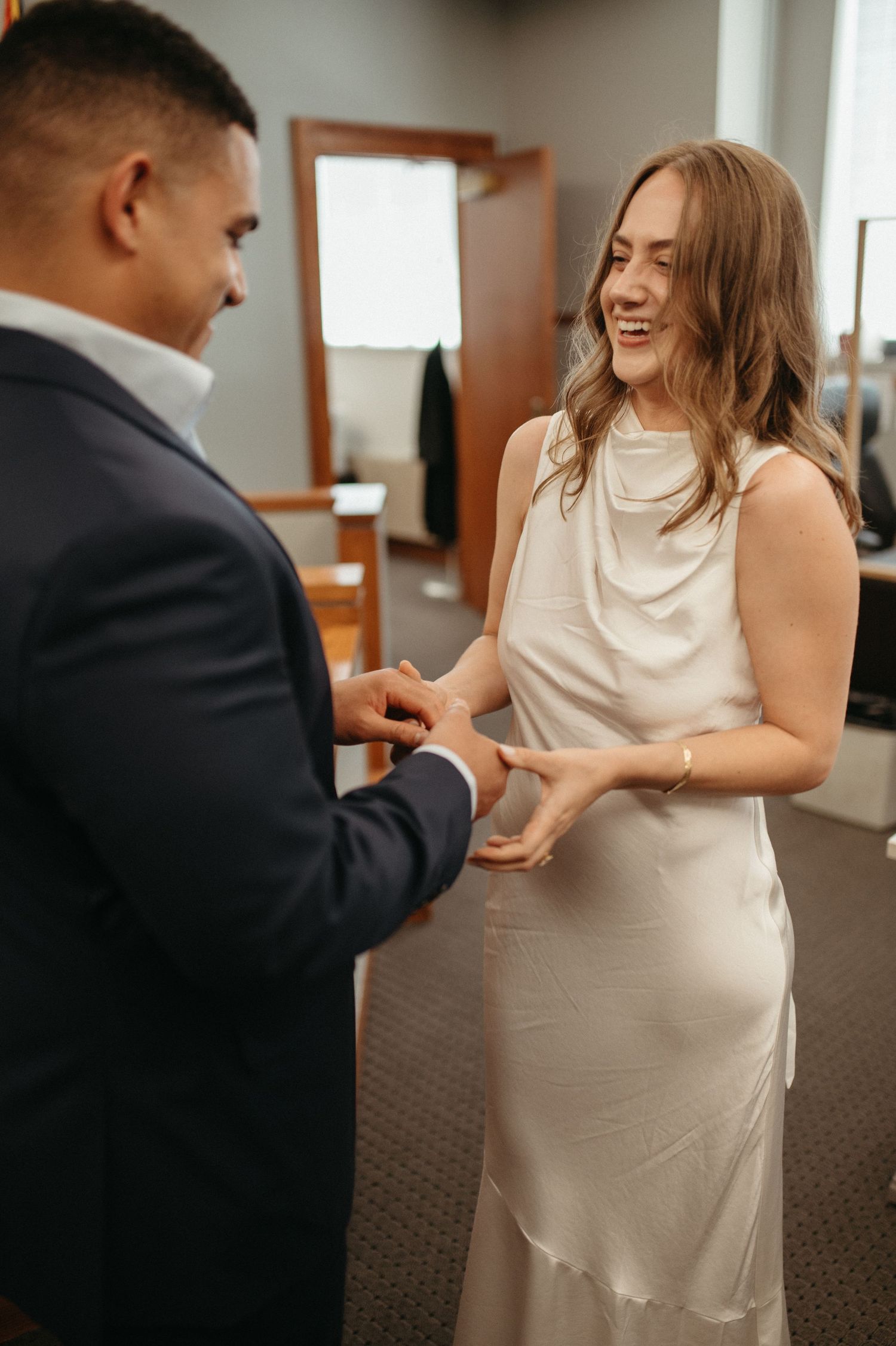 Happy couple exchanges rings during courthouse ceremony.