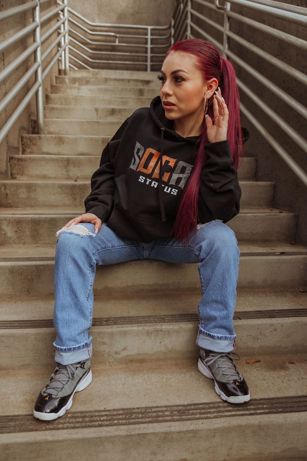 Street style shot on concrete steps featuring black hoodie and classic denim look.