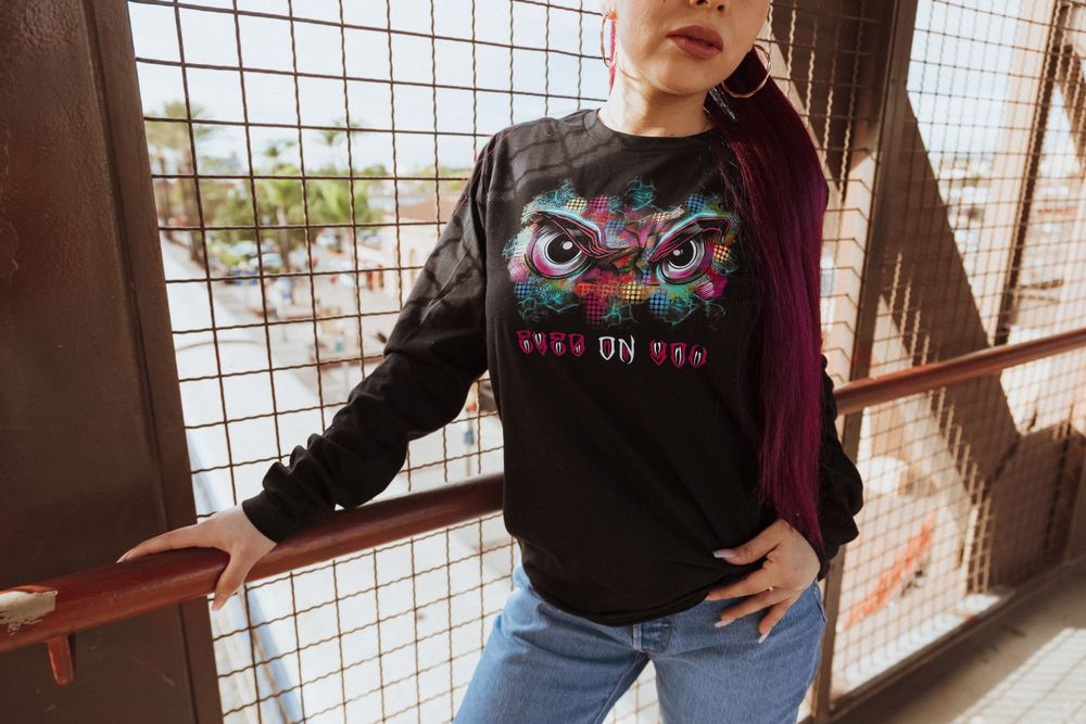 Close-up of graphic t-shirt design with eyes motif against industrial backdrop.