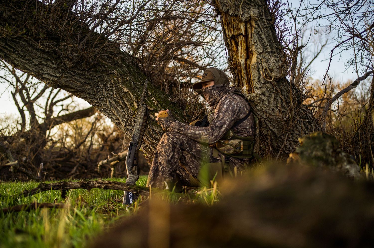 Camouflaged hunter sitting in natural blind waiting for waterfowl.