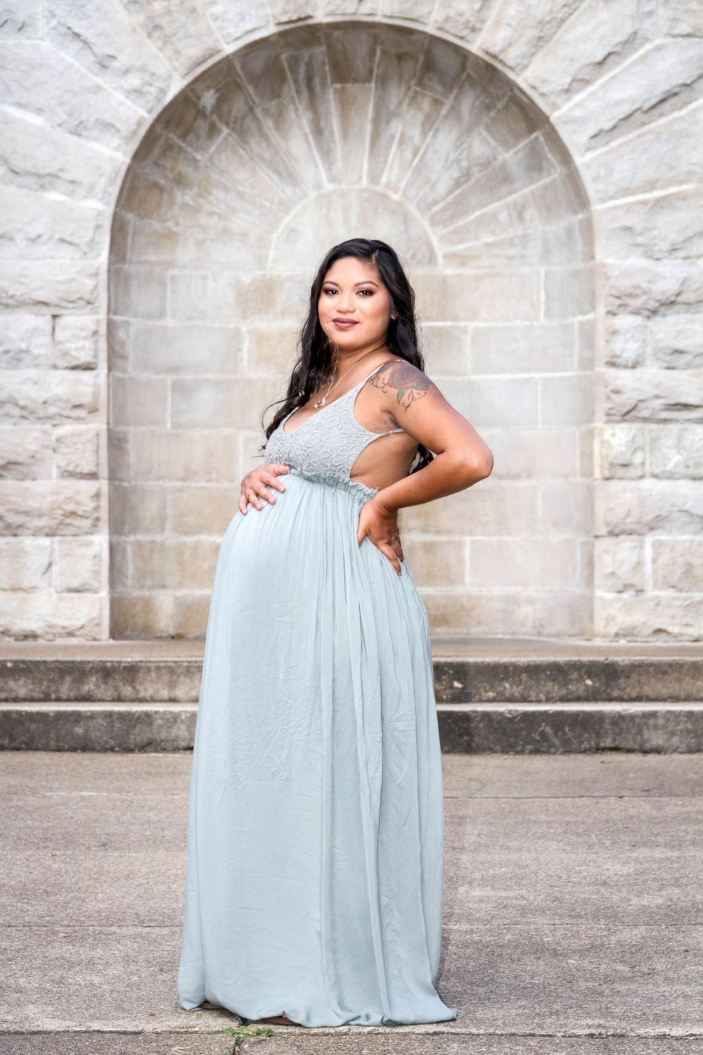 pregnant woman in long dress showing off her belly for maternity photos on Bath House Row in downtown Hot Springs, Arkansas