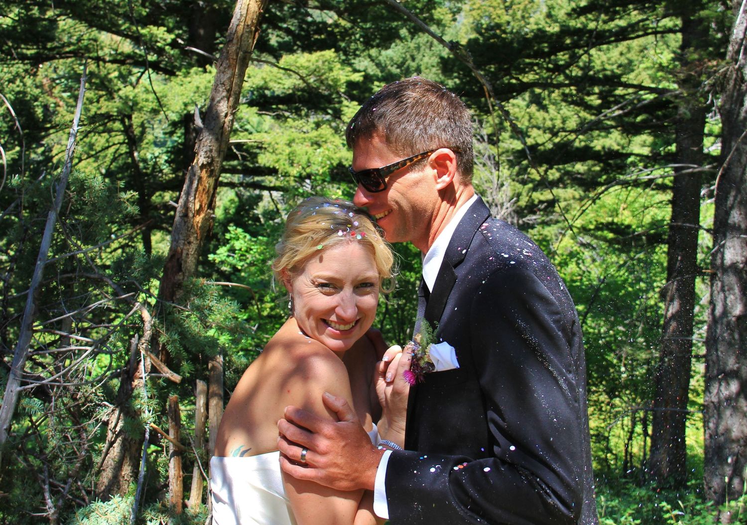 Wedding couple sharing intimate moments in a lush green forest setting.