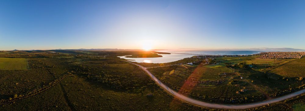 Aerial panoramic view of a coastal landscape at golden sunset with clear blue sky.