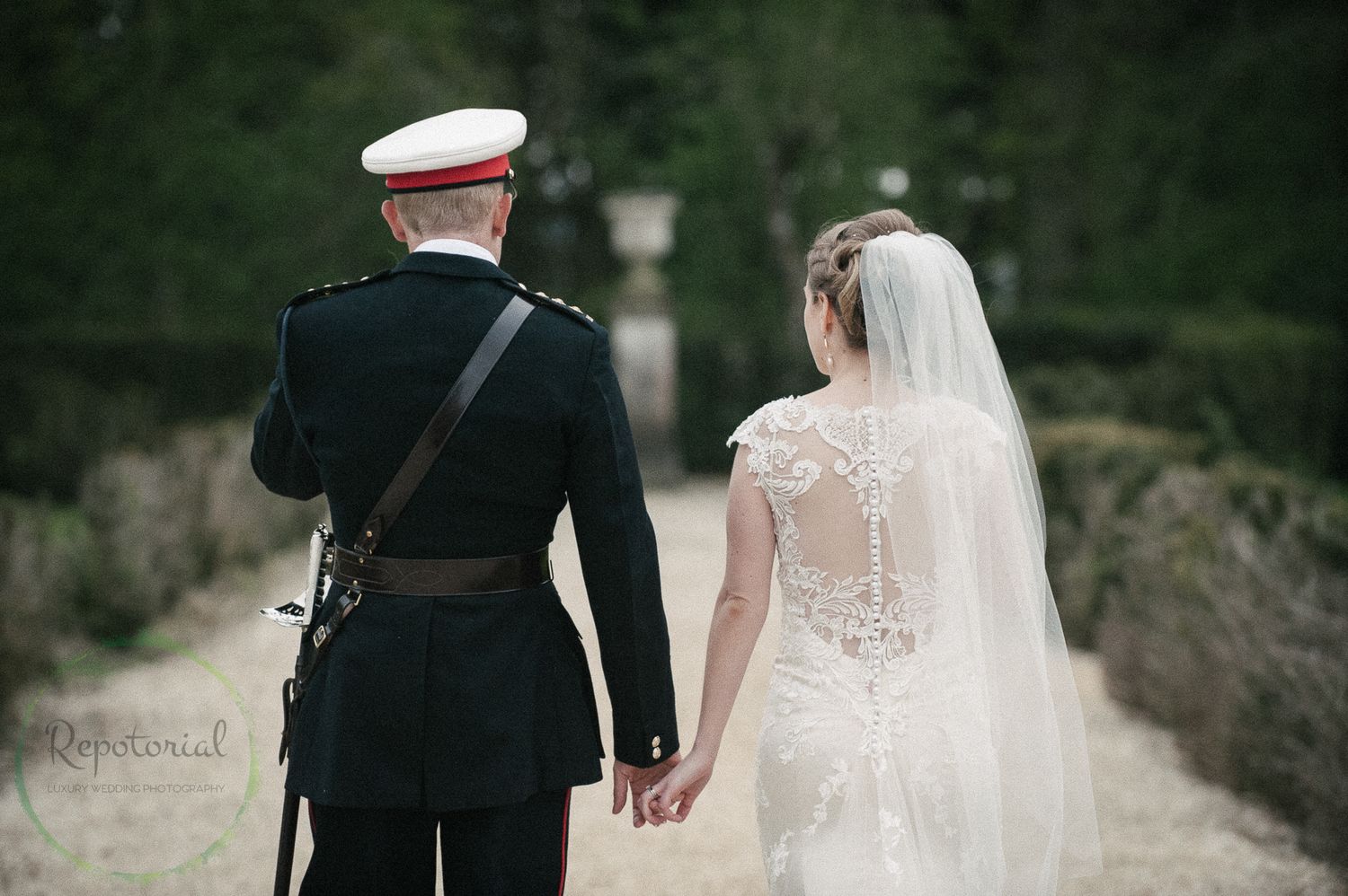 Reportage detail shot of royal marine office groom and bride walking down tree lined pathway
