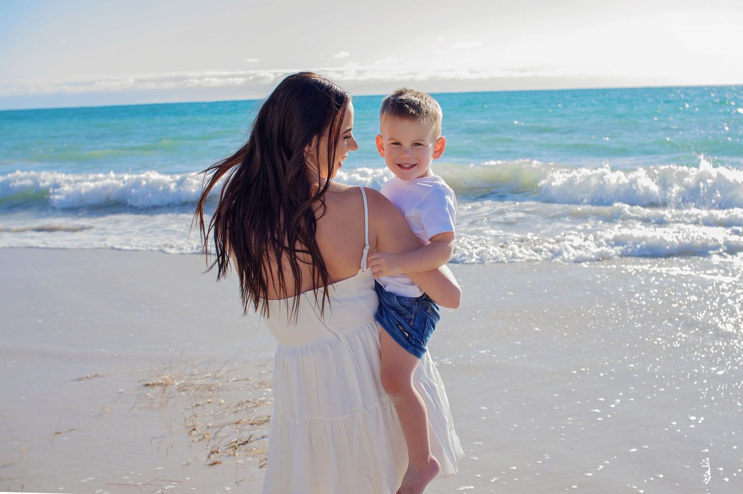 mother holding yougn son smiling on beach