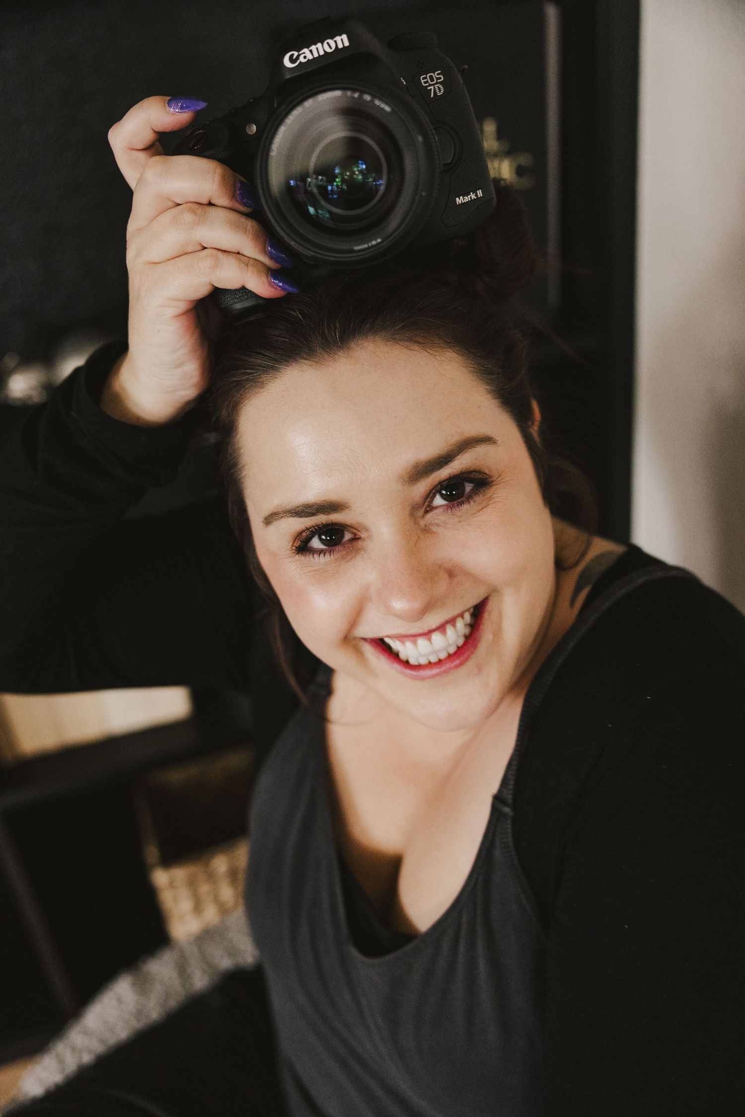 Portrait of photographer holding Canon camera with creative lighting and warm tones. Denver Photographer.