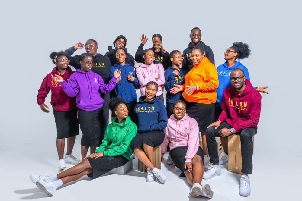 Energetic group of young people in vibrant colored hoodies laughing and posing together playfully.